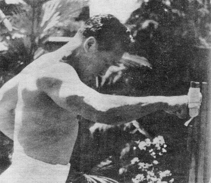 A bare-chested Mas Oyama striking a makiwara post fixed outdoors among trees.