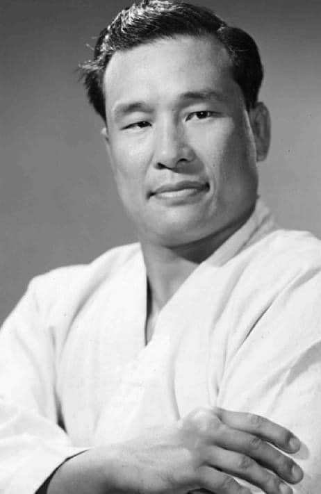 Studio portrait of a young Masutatsu Oyama in a white gi, arms folded.